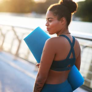 Woman in workout outfit carrying yoga mat