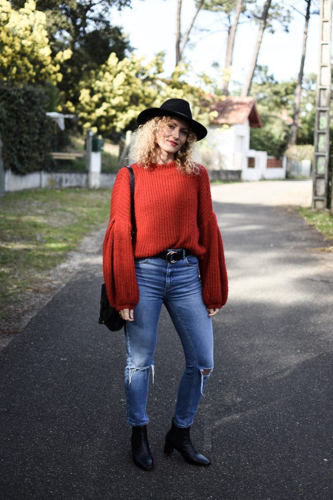 Pull rouge XXL, jean mom et chapeau pour un look minimaliste